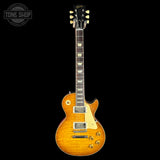 A classic electric guitar with a natural flame maple body, shown against a solid black background. The brand headstock is visible but not clearly legible.