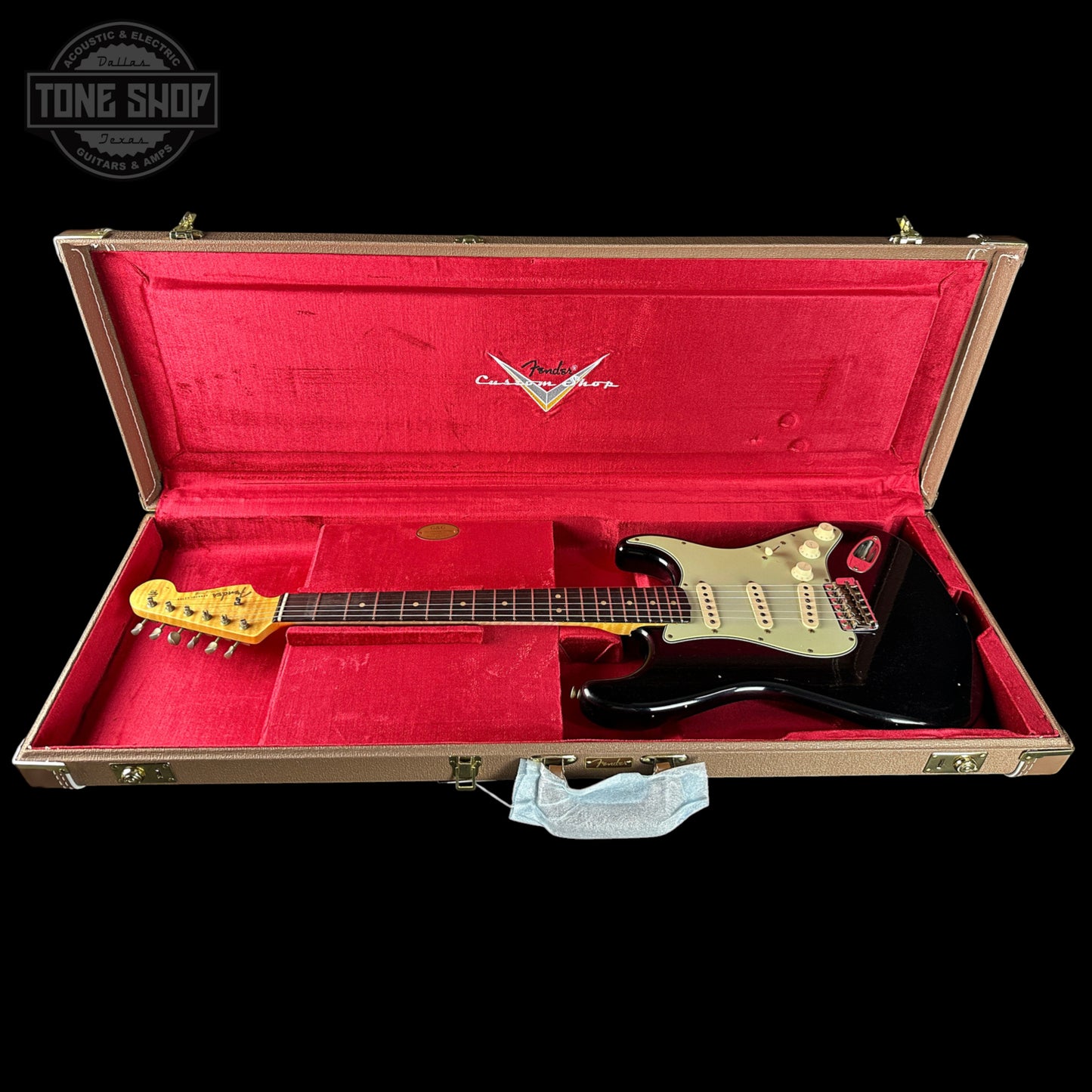 Electric guitar in a red-lined case with a visible brand logo on a black background.