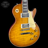 A close-up of a Gibson Les Paul Custom electric guitar with a natural flamed maple top, gold hardware, and a cream pickguard, shown against a black background with a Tone Shop watermark.