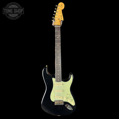 Black electric guitar with a light green pickguard on a black background, featuring the Fender logo.