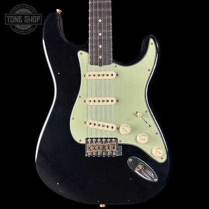 Black electric guitar with a light green pickguard on a black background, featuring the Tone Shop logo.