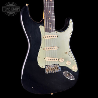 Black electric guitar with a white pickguard on a black background, featuring the Tone Shop logo.