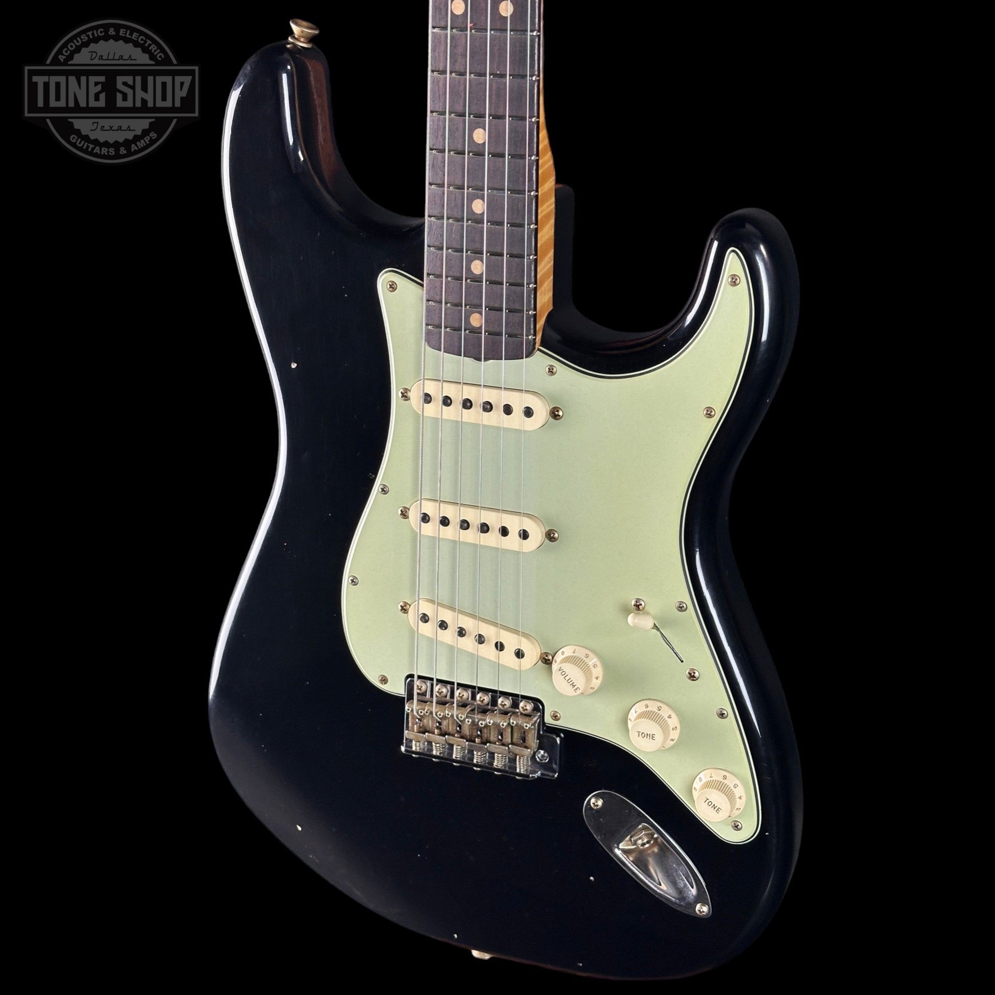 Black electric guitar with a visible brand logo on a black background