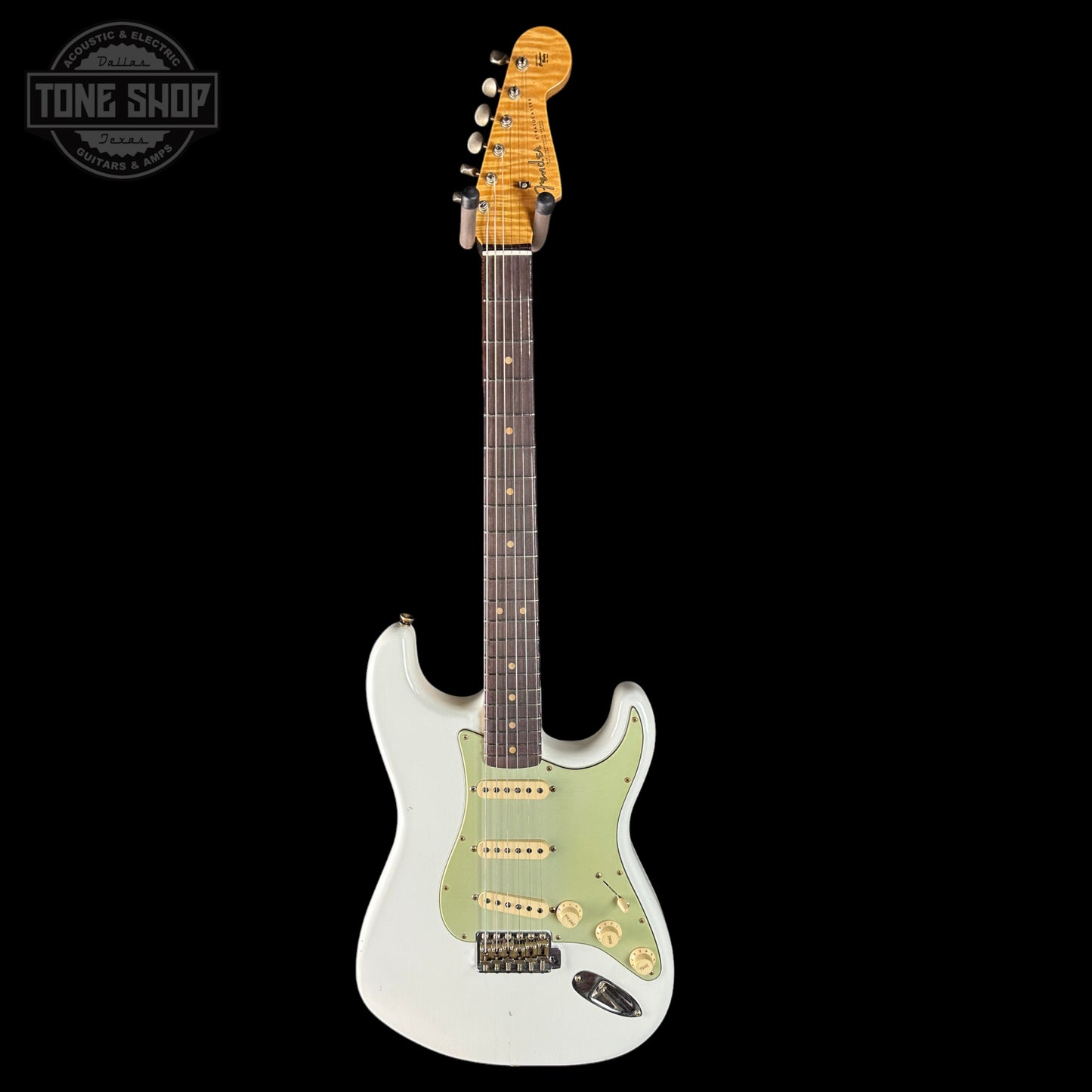 Electric guitar with a white body and green pickguard on a black background, featuring the Tone Shop logo.