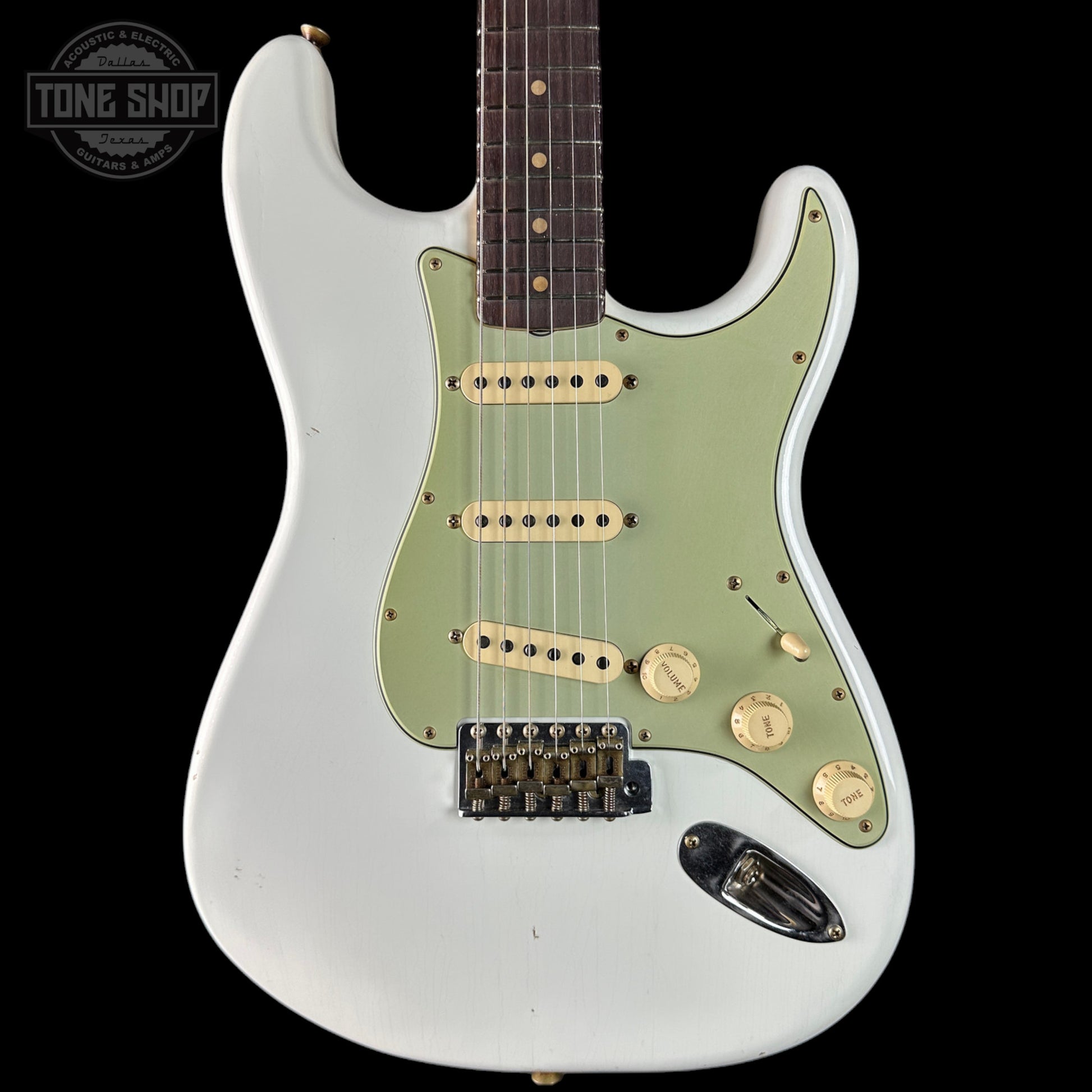 White electric guitar with green pickguard on a black background, featuring 'Tone Shop' branding.