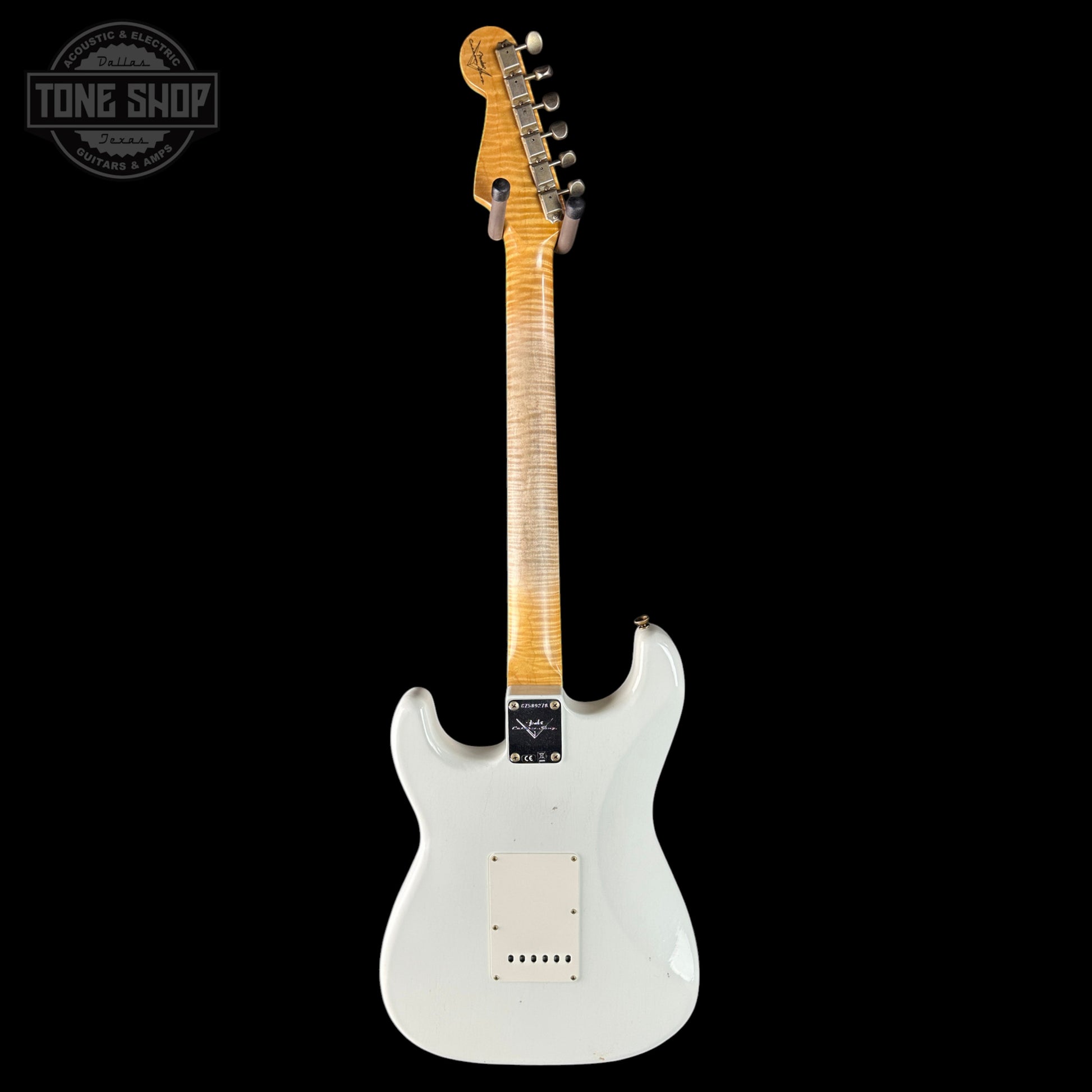 White electric guitar with a black background, featuring the Tone Shop logo.