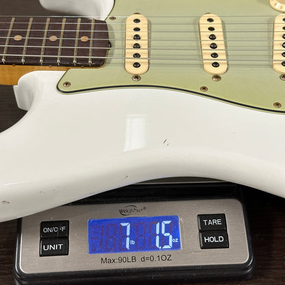 Guitar being weighed on a digital scale with a visible weight reading.
