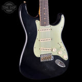 Black electric guitar with a visible brand logo on a black background