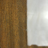 Close-up of a glossy brown wood-grain surface meeting a smooth white reflective surface, with a small visible pinhole or scratch near the seam.