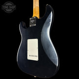 Black electric guitar with a visible brand logo on a black background