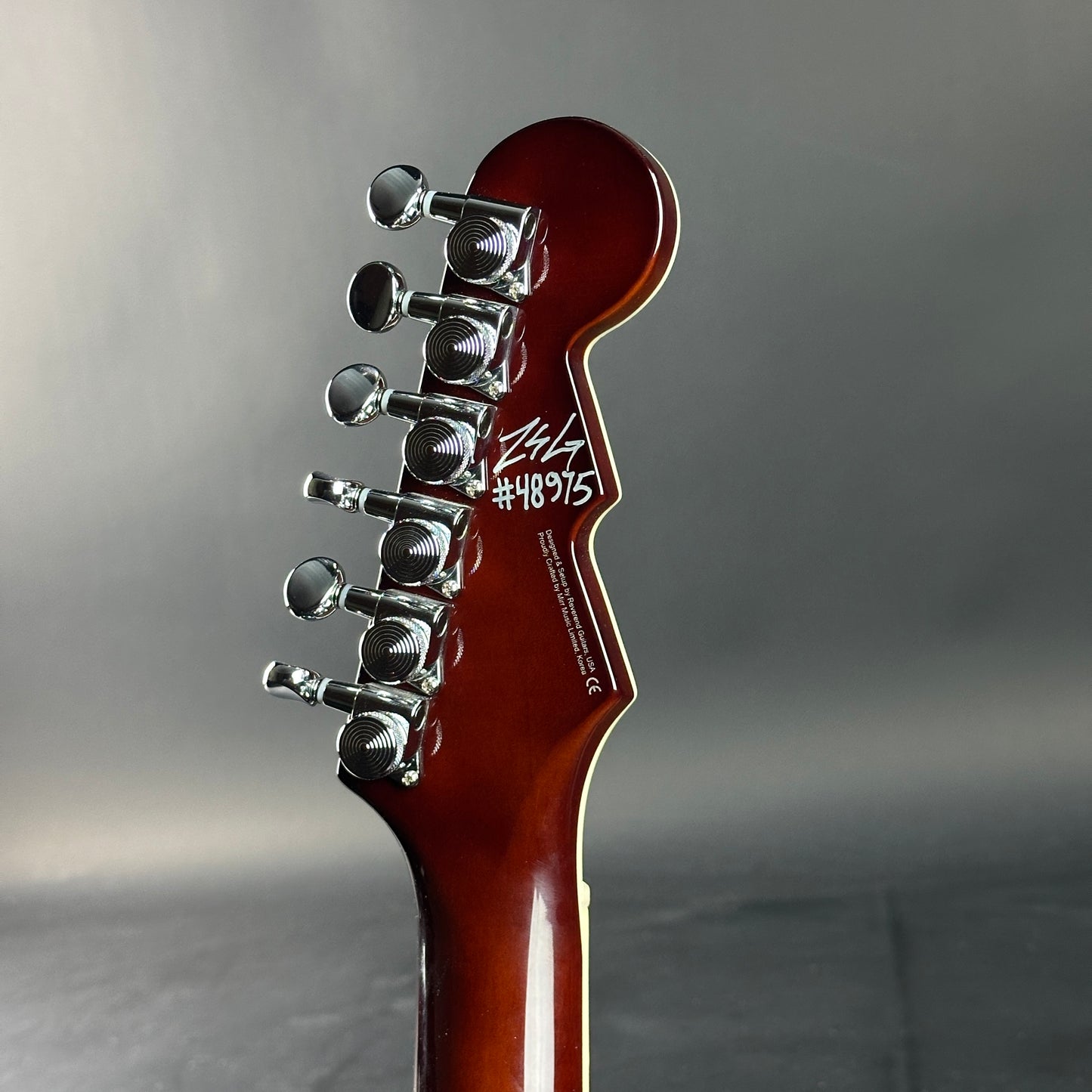 Guitar headstock with tuning pegs on a gray background