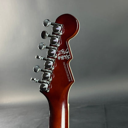 Guitar headstock with tuning pegs on a gray background
