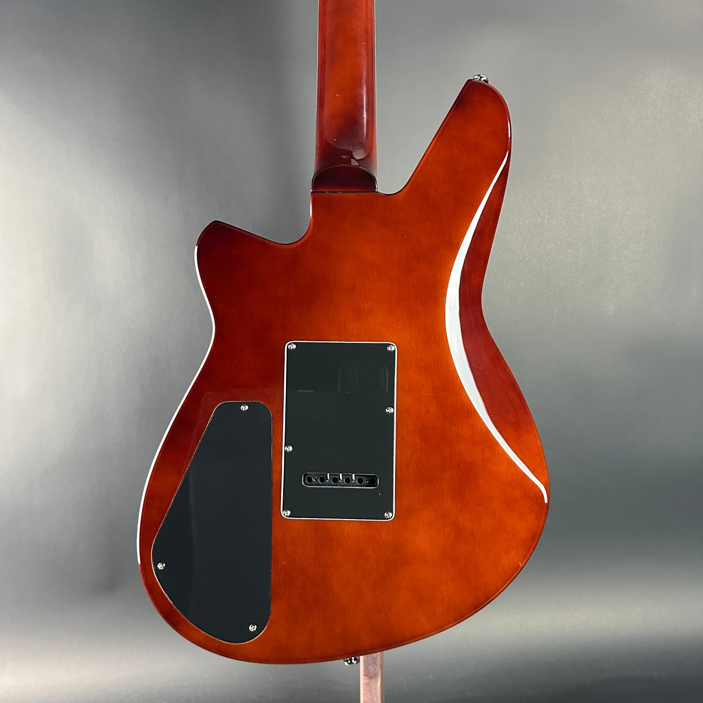 Back view of a brown electric guitar on a gray background