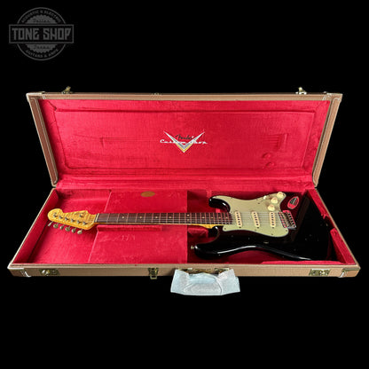 Guitar in a red-lined case with a visible brand logo on a black background