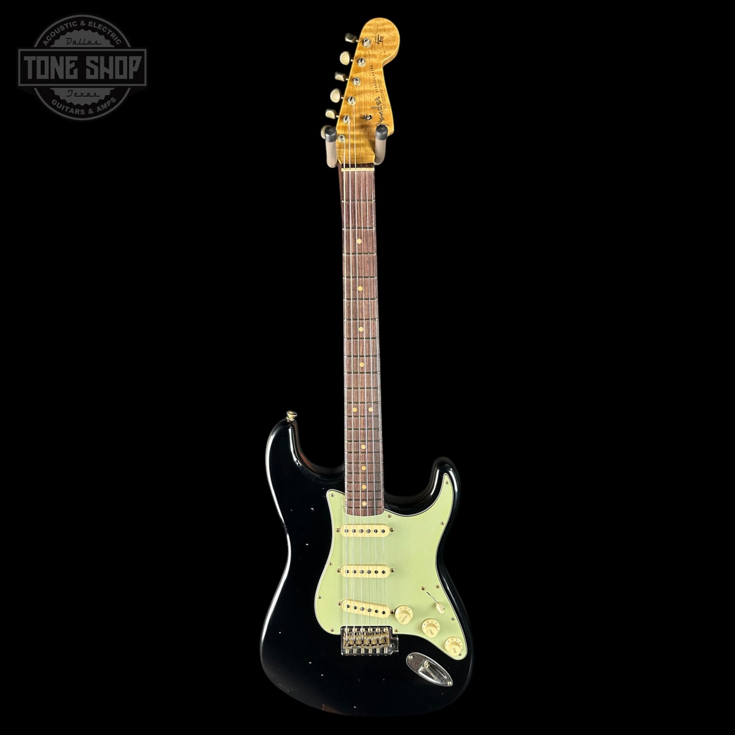 Electric guitar with a black body and green pickguard on a black background