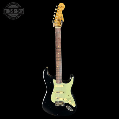 Electric guitar with a black body and green pickguard on a black background
