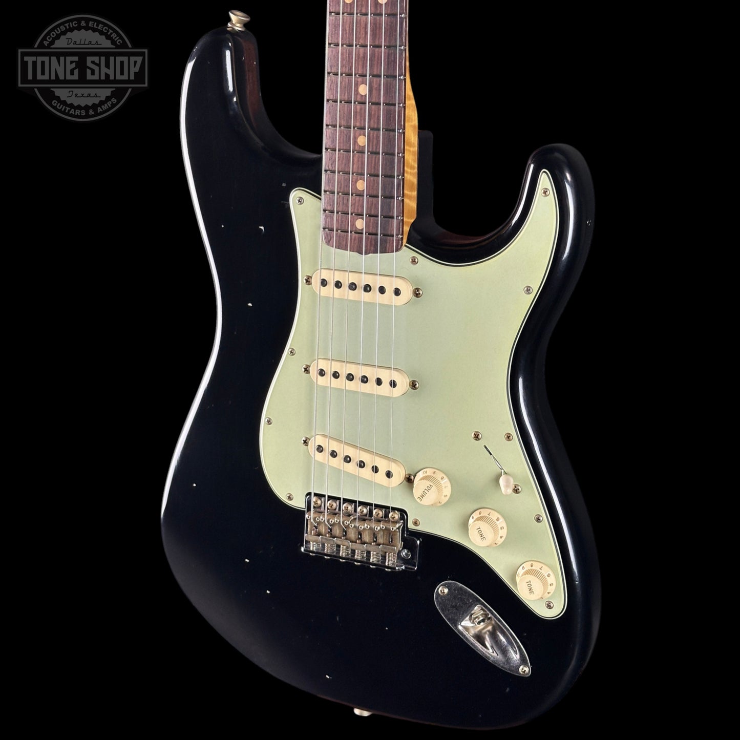 Black electric guitar with a visible brand logo on a black background