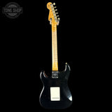 Black electric guitar with a visible brand logo on a black background