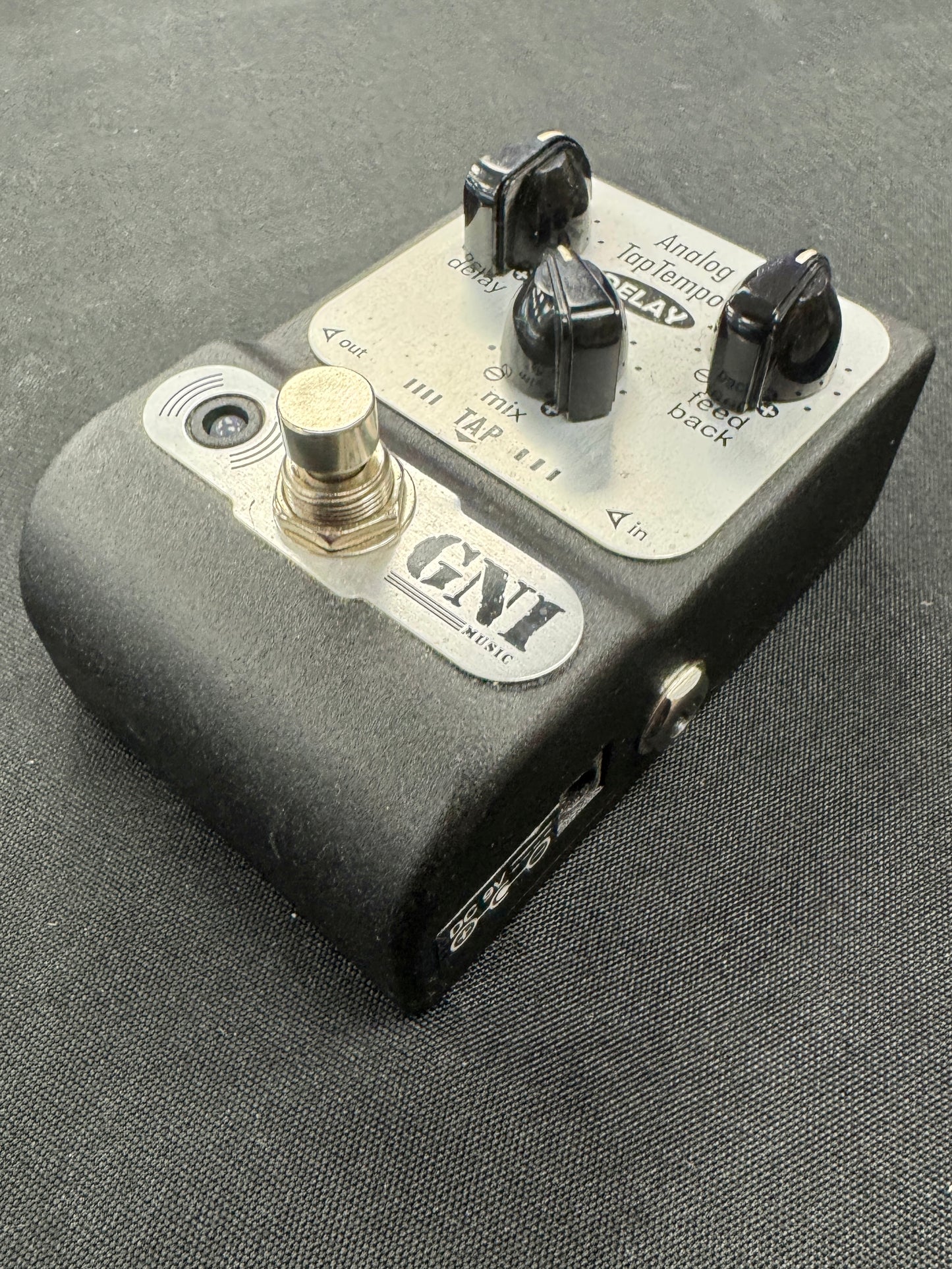 Guitar effects pedal with knobs and a footswitch on a gray surface