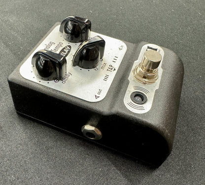 Guitar effects pedal with knobs and switches on a gray background