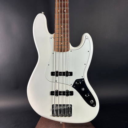 White electric bass guitar with a dark brown neck on a black background