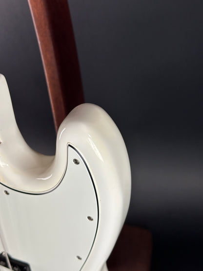 Close-up of a white guitar neck and headstock against a dark background