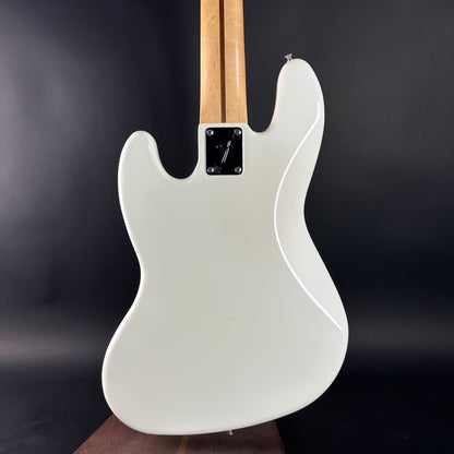 White electric guitar with a wooden neck against a dark background