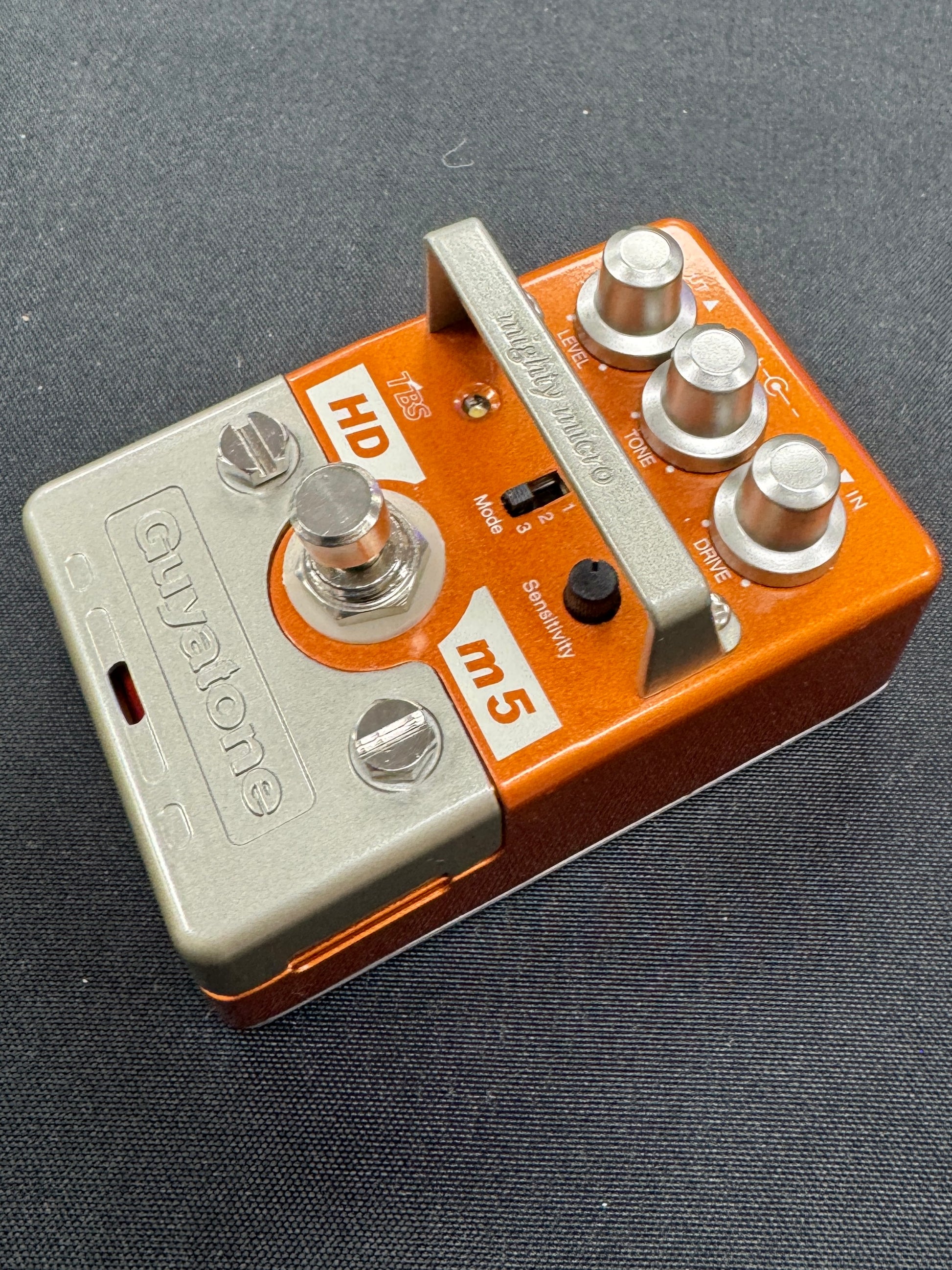 Orange and silver guitar effects pedal on a dark background