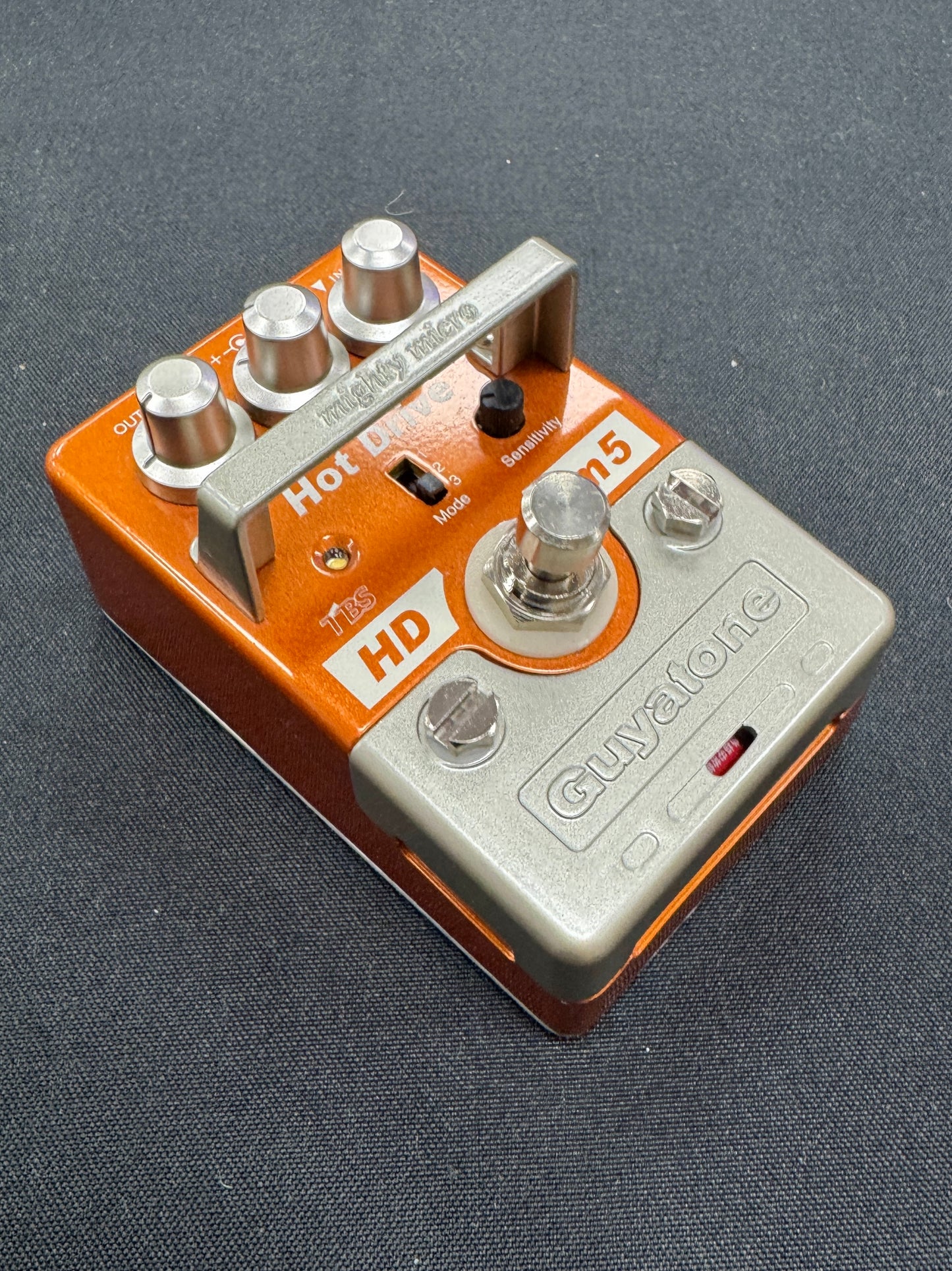 Guitar effects pedal with orange and silver design on a gray background