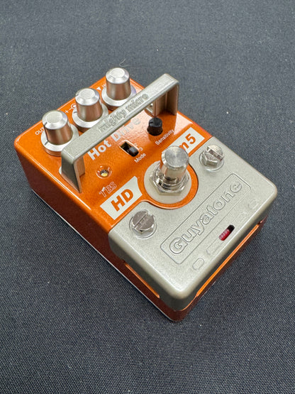 Guitar effects pedal with orange and silver design on a gray background