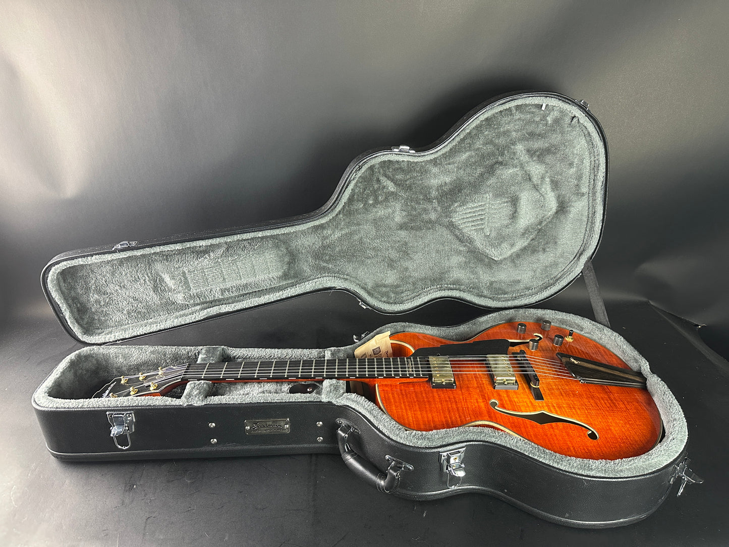 Guitar in an open hard-shell case on a dark surface