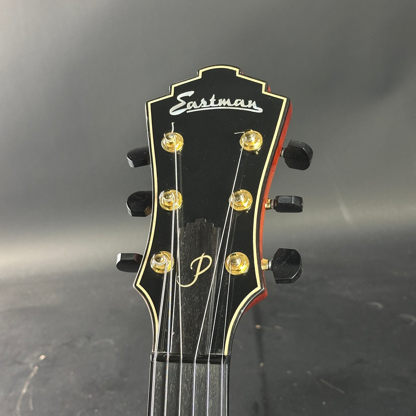 Guitar headstock with Eastman logo on a dark background