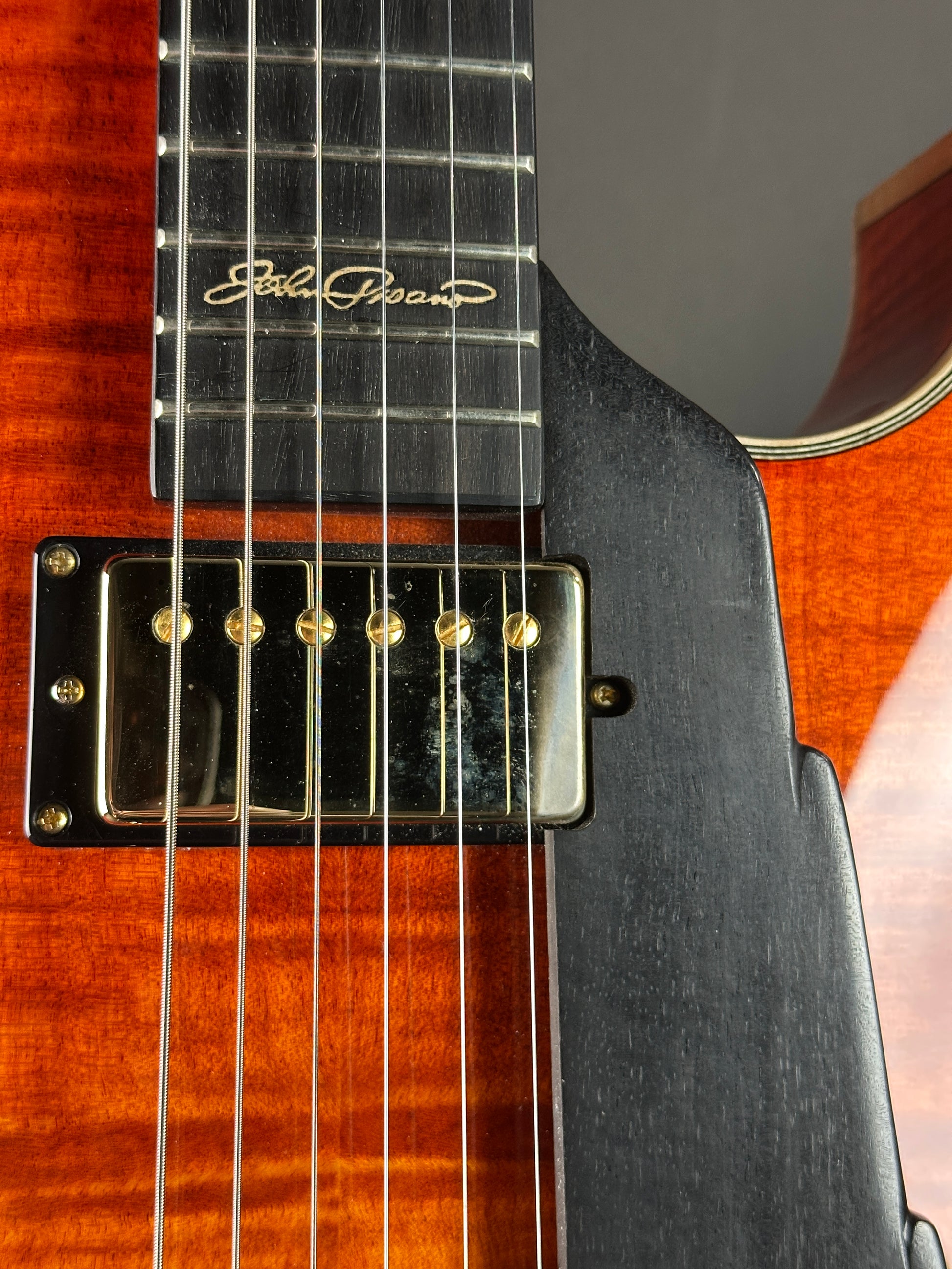 Close-up of a guitar with a visible brand logo on the neck