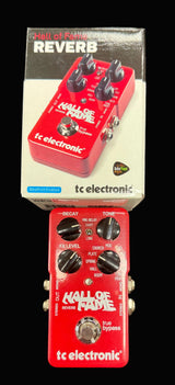 Red guitar effects pedal with 'Hall of Fame Reverb' branding on a dark surface.