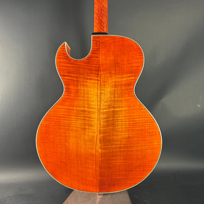 Back view of a wooden acoustic guitar on a dark background