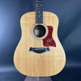 Acoustic guitar with a red pickguard on a dark blue background