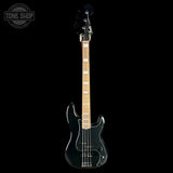 A black electric bass guitar with a maple neck and white block inlays, shown vertically against a solid black background. A Tone Shop watermark is visible in the top-left corner.