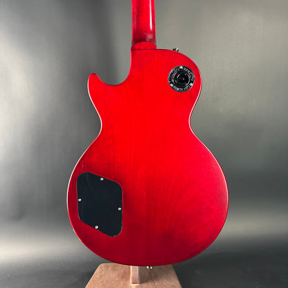 Red electric guitar on a stand with a gray background