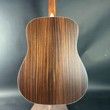 Back view of a wooden acoustic guitar on a dark background