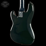 The rear view of a glossy black electric guitar body, featuring a distinctive double-cutaway shape and a chrome hardware plate, set against a solid black background.