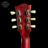 Close-up rear view of a guitar headstock with six cream tuning pegs and silver tuning machines on a glossy red finish, shown against a black background with a Tone Shop watermark.