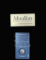 Blue Moollon guitar pedal with brown box labeled 'Moollon Musical Instrument Contempo Series' on a dark background