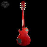 A red electric guitar shown from the back, featuring a glossy cherry red finish, a black pickguard, and gold tuning pegs, set against a solid black background with a Tone Shop watermark in the top left corner.