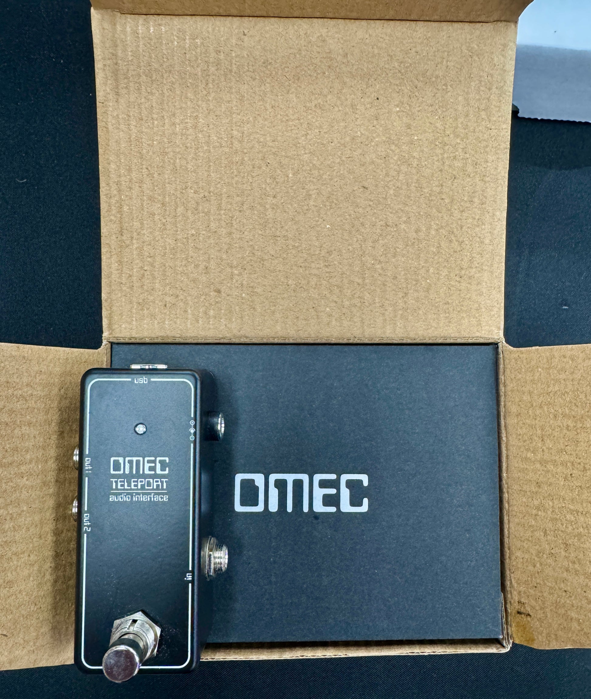 OMEC guitar effects pedal on a cardboard surface