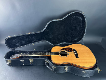 Acoustic guitar in an open black case on a gray background