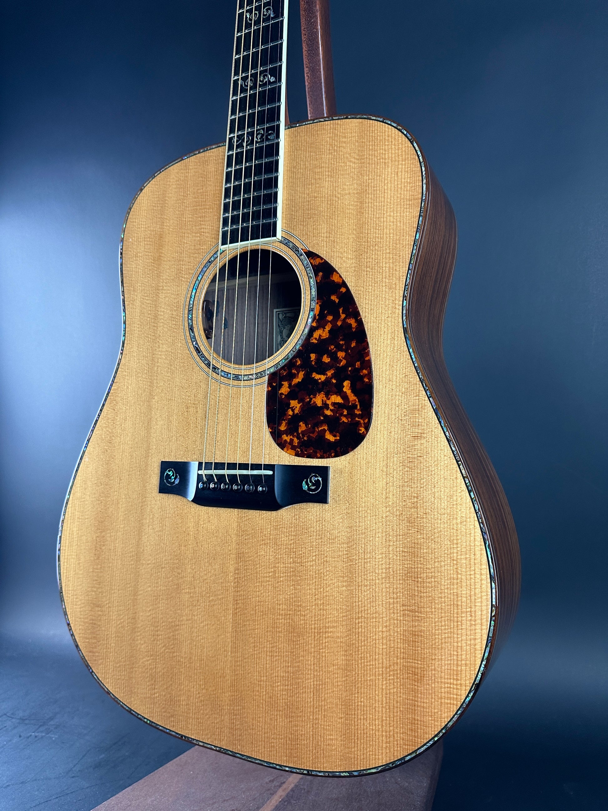 Acoustic guitar with tortoiseshell pickguard on a blue background