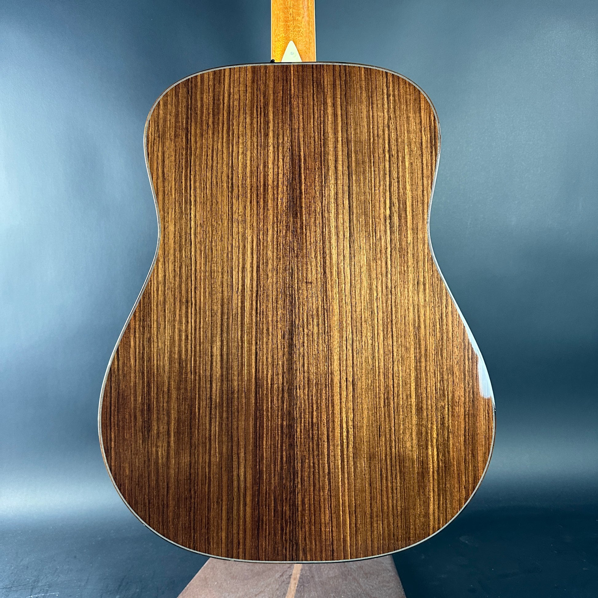 Close-up of a wooden acoustic guitar on a blue background