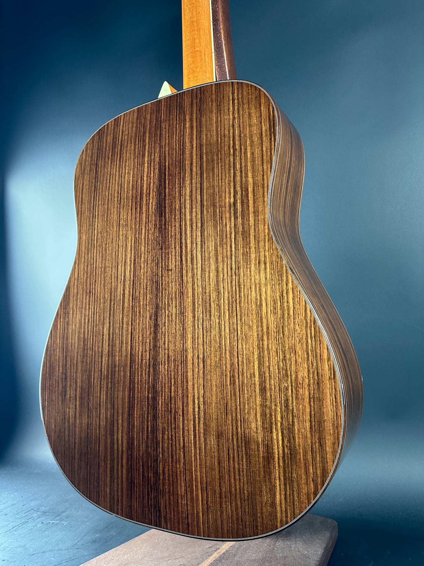 Close-up of a wooden acoustic guitar body on a blue background