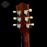 Close-up of the headstock of a six-string acoustic guitar, showing six silver tuning pegs with cream-colored knobs and a glossy dark brown wood finish, set against a solid black background.