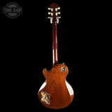 The back view of a Gibson Les Paul Custom electric guitar with a glossy reddish-brown wood finish, shown against a solid black background. A Tone Shop watermark is visible in the top-left corner.